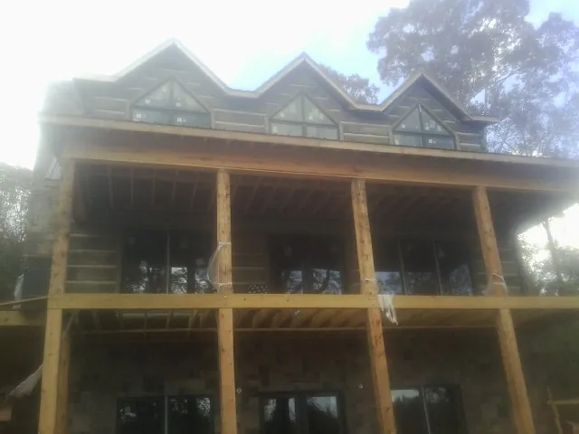Dormers and porch framing on a large log home under construction — Roof Coating work by our crew in Minong