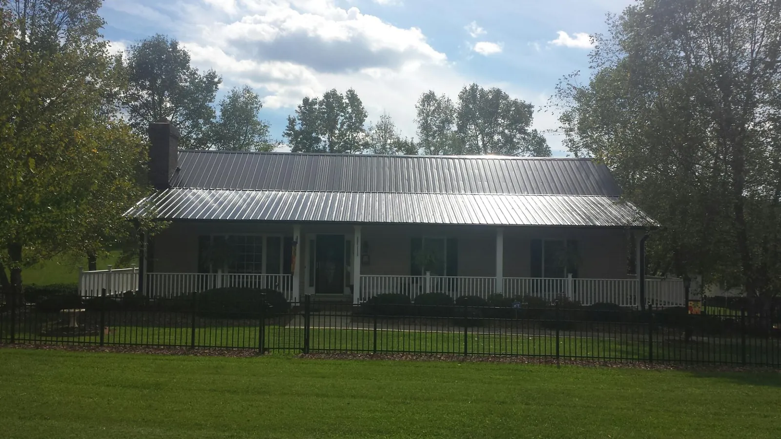 Gray metal roof on a brick ranch with a full width front porch — Gutter Guard Installation work by our crew in Minong