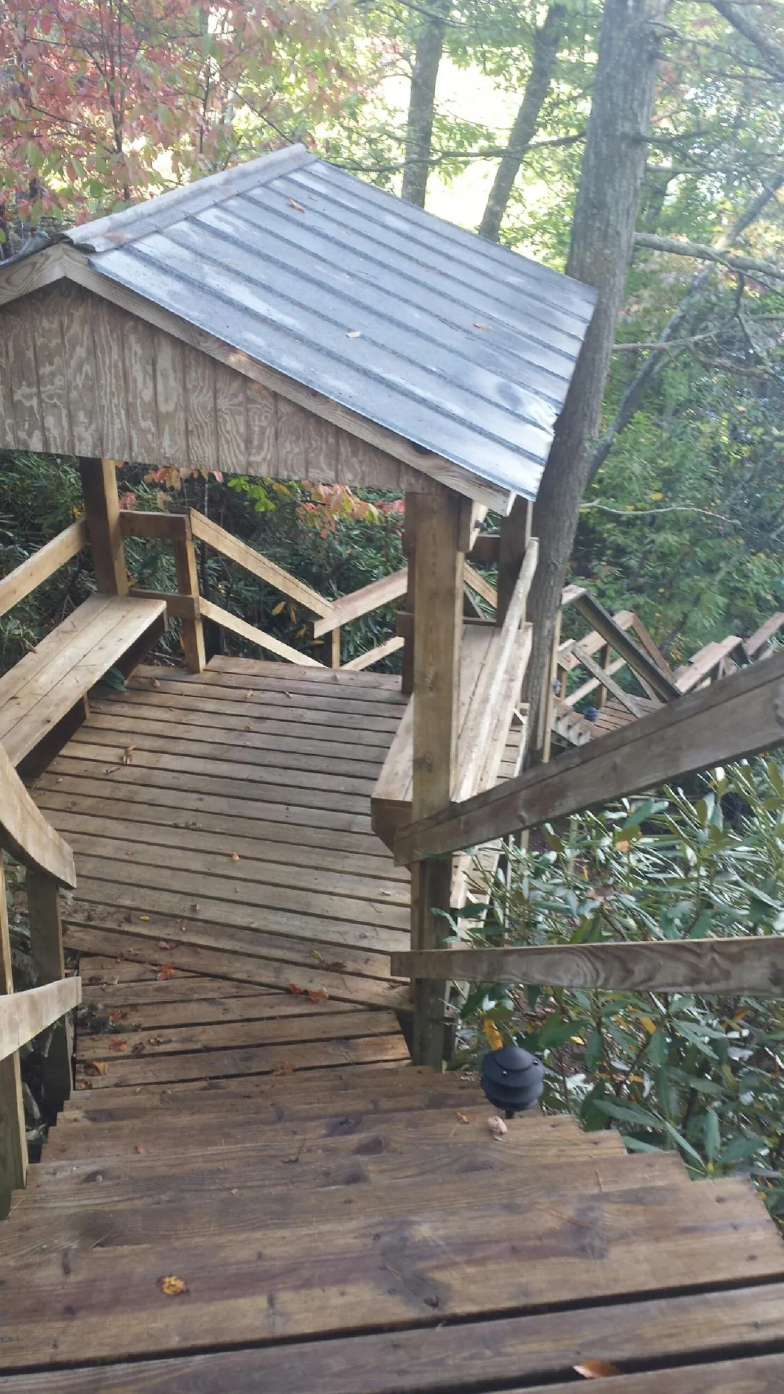 Metal roofed shelter over wooden steps on a wooded walkway — Skylight Repair & Installation work by our crew in Minong