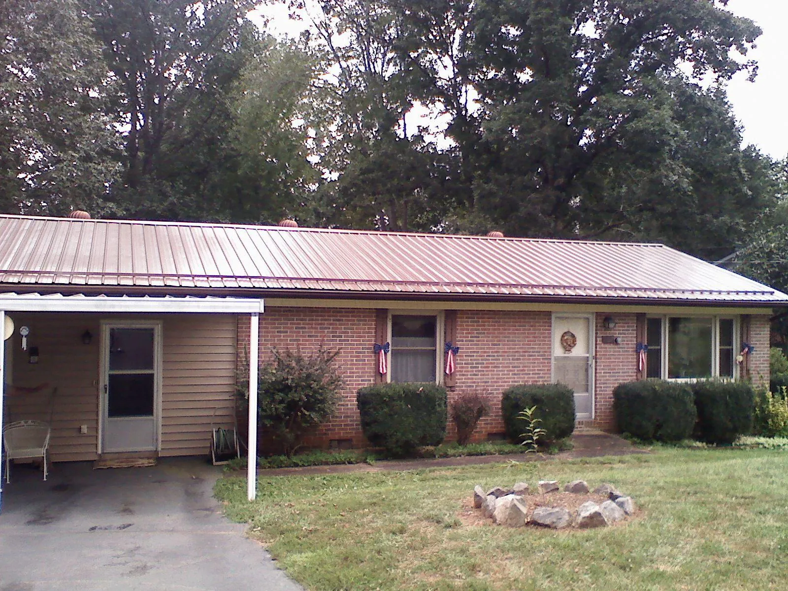 Bronze metal roof and carport on a brick ranch home — Roof Repair work by our crew in Minong