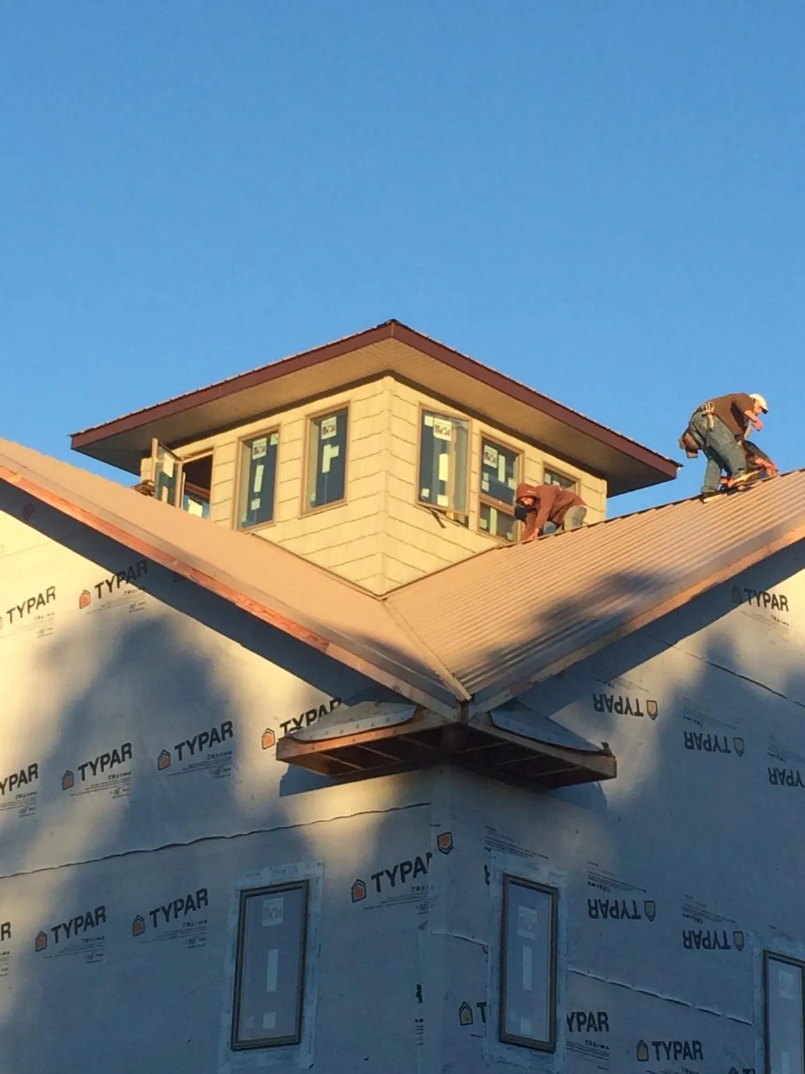 Roofers working around a rooftop cupola on a new metal roof at sunset — Roof Waterproofing in Minong by Roofing Brothers